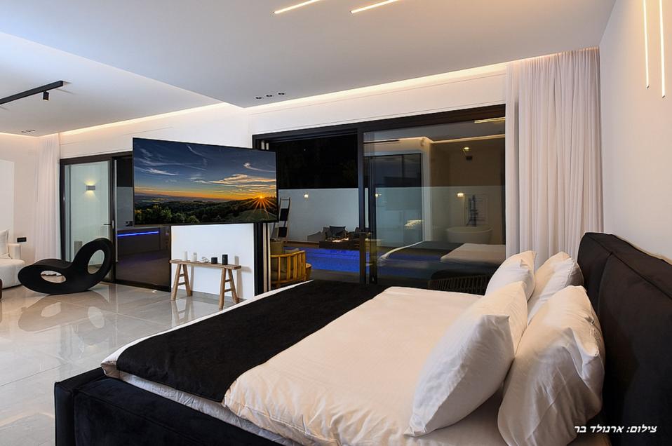 מיטה זוגית רחבה מול מסך טלוויזיה מתכוונן