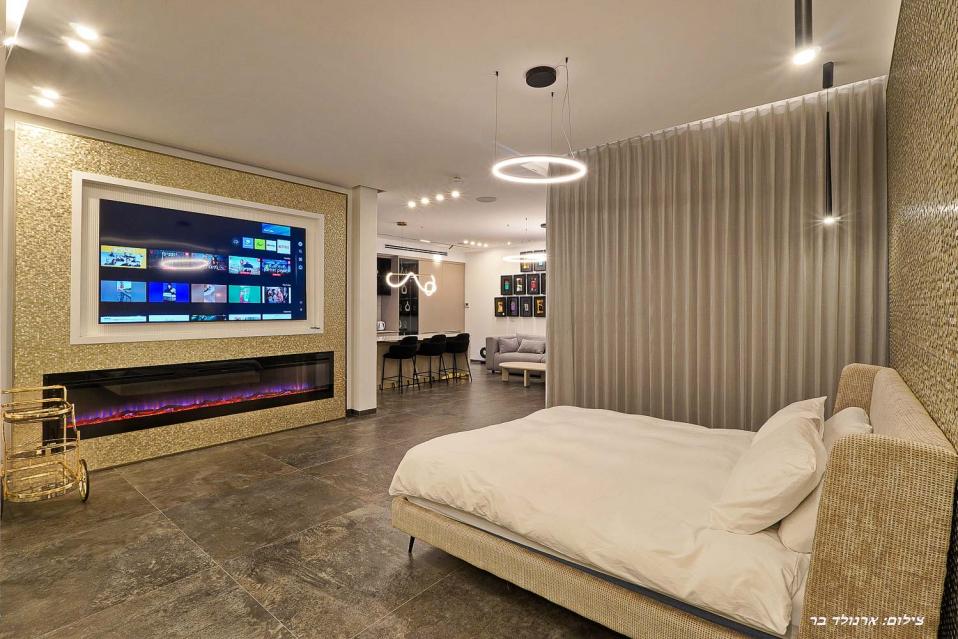 מסך ענק מול מיטת קינג סייז מפנקת