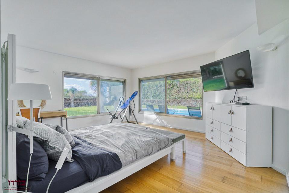 חדר שינה מואר עם חלונות ענק ונוף לחצר